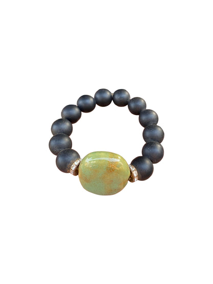 Handmade beaded bracelet from Ghana, black wooden beads with a green glass bead (unisex)